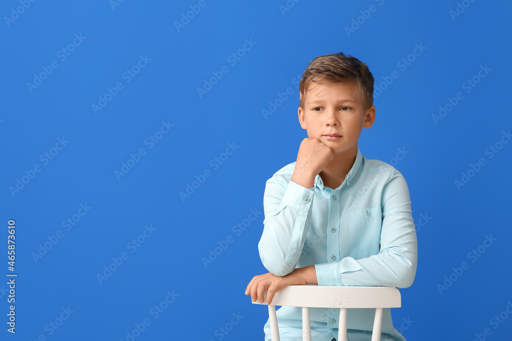 Sticker thoughtful little boy sitting in chair on blue background