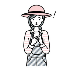 立ってスマートフォンを操作して何かに気づいて驚いた農家の女性