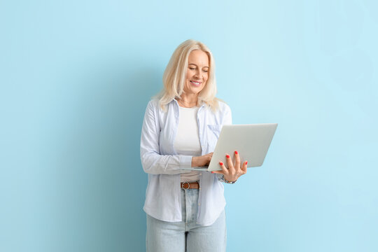 Beautiful Mature Woman Using Laptop On Blue Background