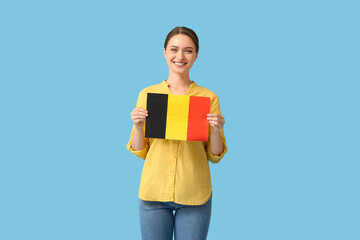 Young woman with flag of Belgium on color background