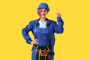 Female electrician pointing at something on color background