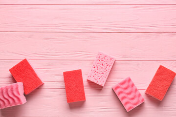 Pink cleaning sponges on color wooden background