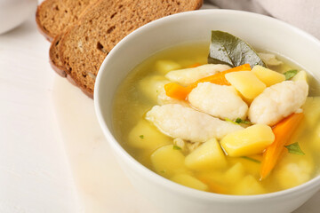 Bowl of tasty dumpling soup on light background, closeup