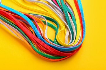 Many different shoe laces on yellow background, closeup