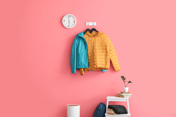 Blue and yellow jackets hanging on pink wall in stylish hallway - Powered by Adobe