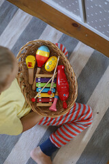 Boy takes musical instruments from a shelf in a Montessori school. Home education.