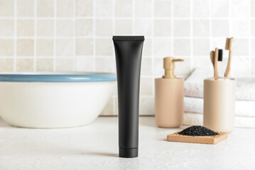 Fototapeta na wymiar Black toothpaste with activated carbon on table in bathroom