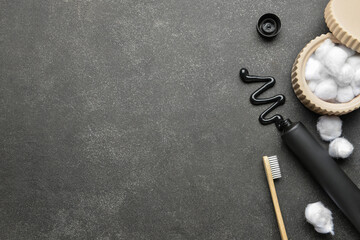 Black toothpaste with activated carbon, brush and cotton balls on dark background