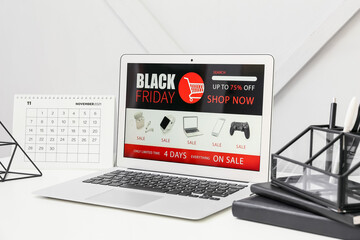Laptop with open page of online store, calendar and organizer on table. Black Friday