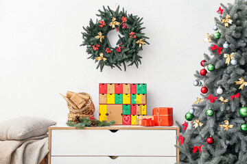 Advent calendar with Christmas gifts on shelf near light wall