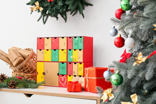 Advent calendar with Christmas gifts on shelf near light wall