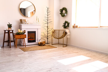 Electric fireplace and stylish armchair in room decorated for Christmas