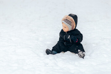 Fototapeta na wymiar Adorable Cute Baby Sitting in the Snow in Winter Season