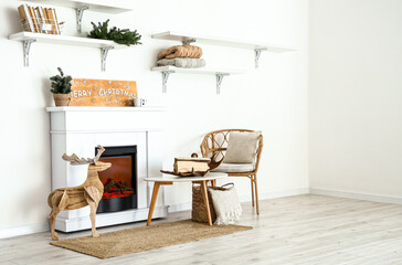 Fireplace and board with text MERRY CHRISTMAS in interior of light room
