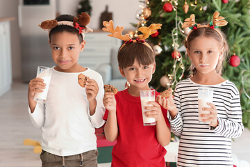 Little children with cookies and glasses of milk at home on Christmas eve