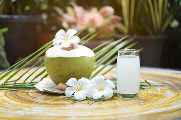 Coconut water in glass .coconut drink with flower on table.