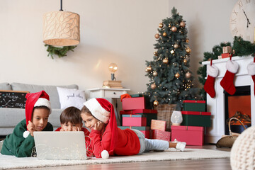Cute little children with laptop watching cartoons at home on Christmas eve