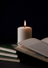 candles with flame, and reading book on desk, black background. (focus on candle).