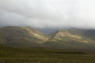 Mountains in Connemara National Park with low cloud and sunshine selective focus