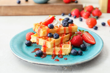 Plate of tasty Belgian Waffles with berries on table