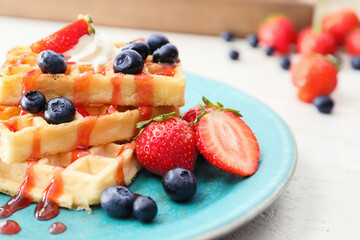 Plate of tasty Belgian Waffles with berries on table