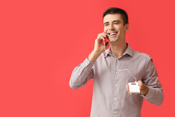 Young man with phone and power bank on color background