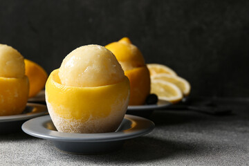 Plates with tasty ice creams in lemon peels on dark background
