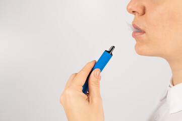 Caucasian woman smokes disposable vape on white background. Alternative device for smoking.