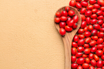 Fresh rose hip berries and spoon on beige background, closeup