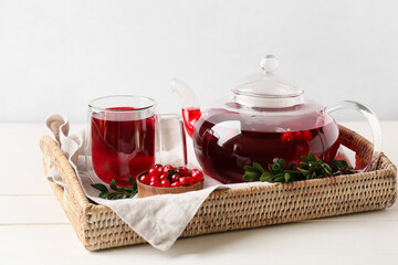 Glass cup of tasty lingonberry tea, pot and fresh berries on table