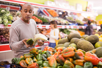 Buyer selects ripe bell peppers in the vegetable section of the supermarket