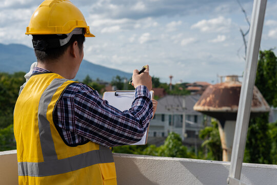 Professional engineers, architects, workers wearing helmets and paperwork in hand with pens at a home construction site.