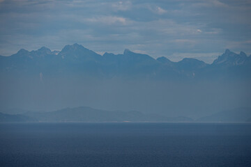 Fototapeta na wymiar mountain range over the horizon by the ocean cover in hazy atmosphere near dawn