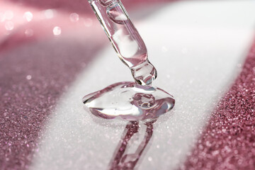 Cosmetic pipette with a pink on dark background.
