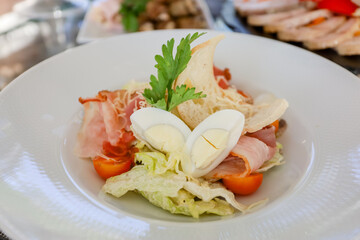 Egg, croutons, tomato, ham salad in a white plate on a table. High quality photo