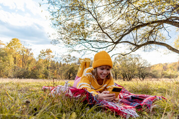 Happy girl takes video on the camera of his smartphone. Cozy slow lifestyle concept. Picnic in the meadow.