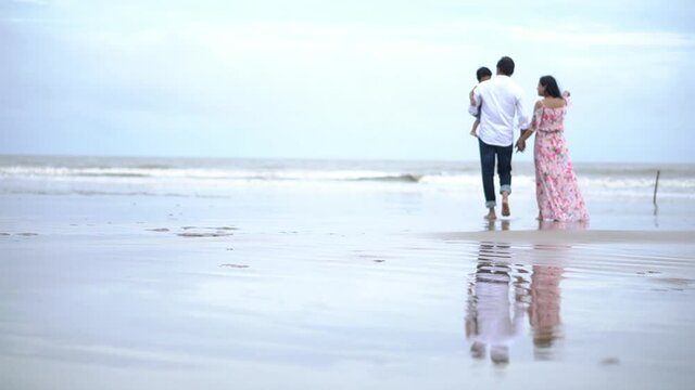 Asian family on vacation. Beautiful father carrying little baby boy on shoulder walking on the beach together with happy and smile. Soft touch, love care, protection of mom and child relationship.