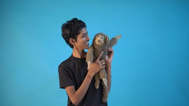 Indian Puppet teenager relaxing with his puppet monkey in Blue Color Background Studio.