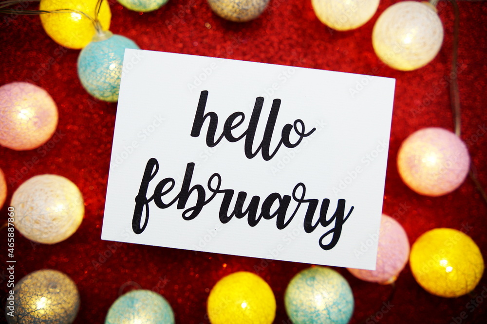 Poster hello february text on paper card top view on red bokeh background