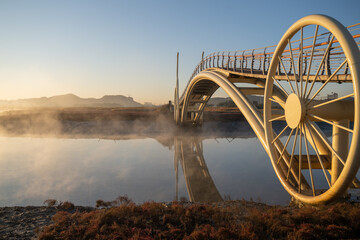 Bicycle-shaped bridge with water fog rising from the beach