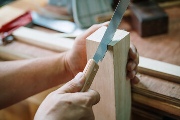 carpenter using Japanese saw or pull saw ,Crosscutting on wood on table,woodworking concept