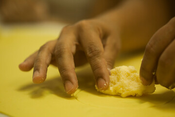 Human Hands making Raw and dry capeletti pasta on kitchen table