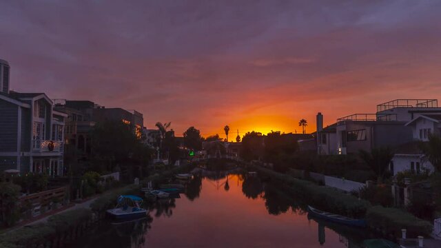 Time lapse shot of Venice Canal with docking boats and luxury apartments during beautiful red fired sunset - Day to night timelapse in California,Usa