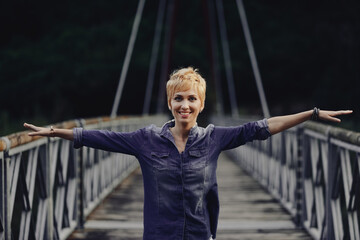 portrait of young woman on bridge and arms outstretched