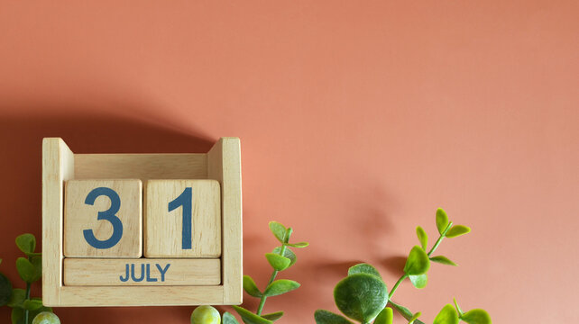 July 31, Date design with calendar cube and leaf on orange background.