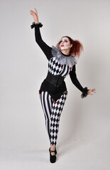   halloween, character, costume, figure pose, posing, portrait, gesture,  isolated,  magical, dynamic movement,  isolated,  studio background,  red hair, circus, theatre, jester, clown,  
full length,