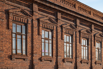 Brick wall of an old 19th century building with large windows. Wall of an old red brick building with five windows