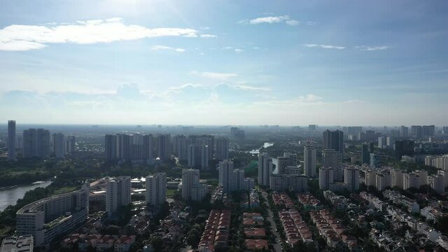 Drone fly in shot of Ultra modern city with river, green space,  high rise buildings and urban sprawl seen from the air on a sunny day.