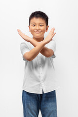 Kid crossed hands, posing stop sign with smile on white background