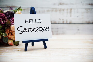 Hello Saturday text with flower bouquet on wooden background © may1985